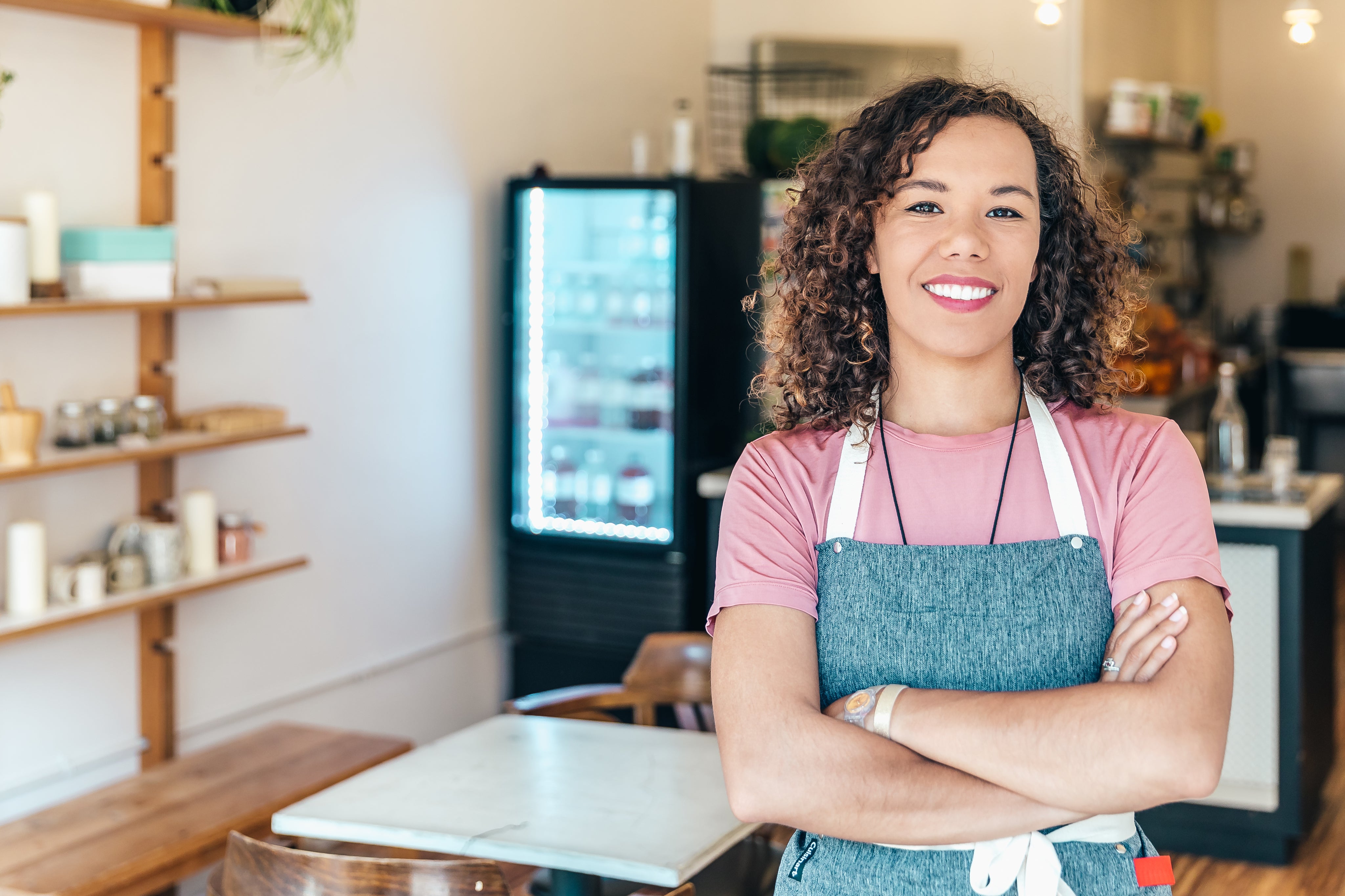 a-barista-smiles-proudly-stood-in-her-cafe.jpg