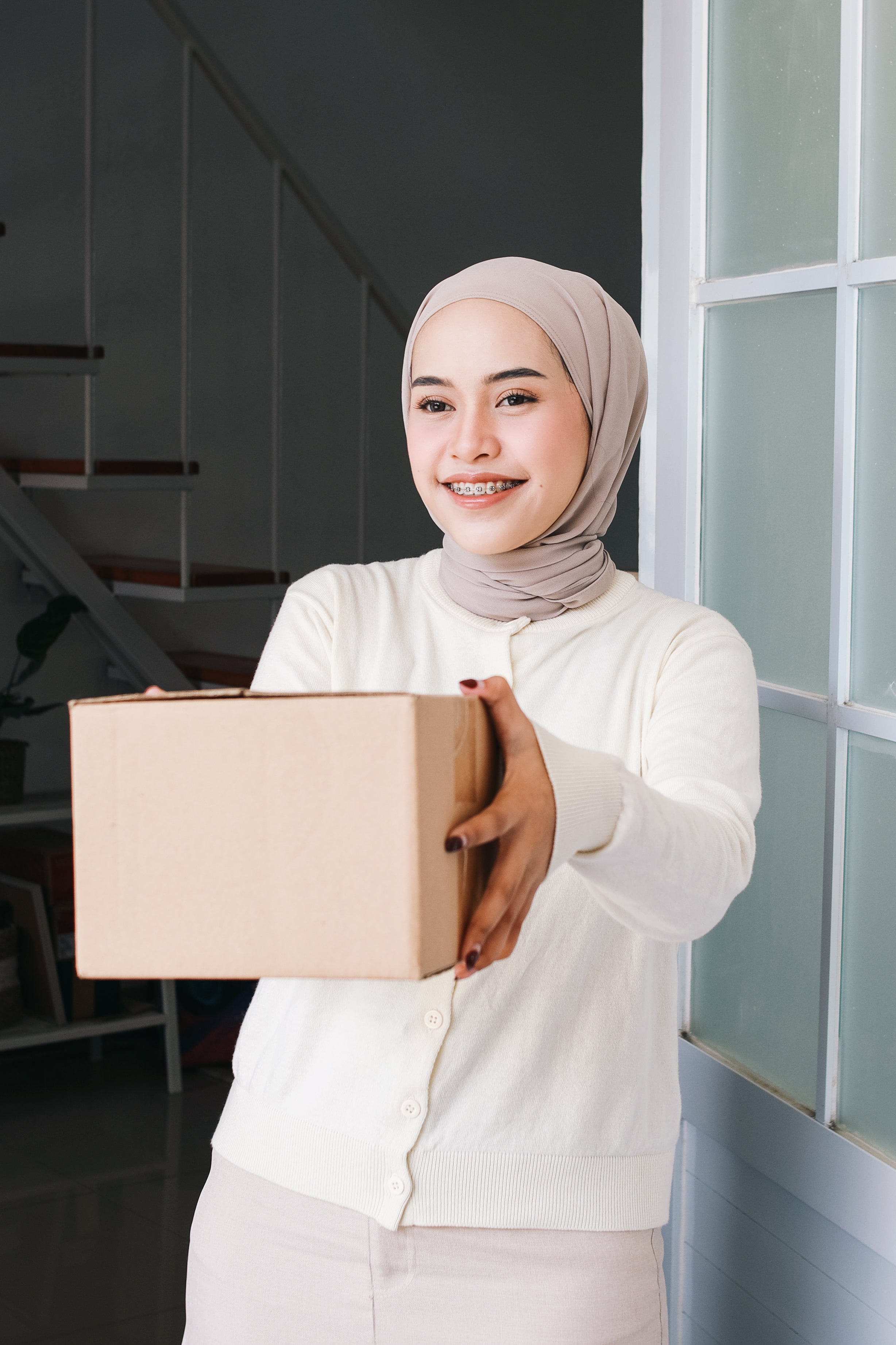 muslim-woman-with-braces-giving-box-package-to-sen-2024-02-08-15-15-55-utc.jpg